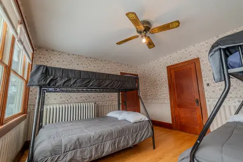 Twin-over-full bunk bed under a ceiling fan beside a wood door