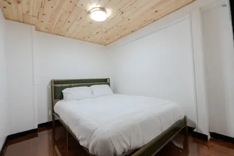 Lower-level bedroom with a bed, two pillows, and a pine ceiling