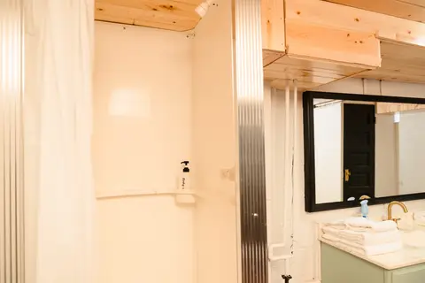 Lower-level shower stall with a curtain beside the vanity