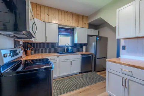 Kitchen with white cabinets, butcher-block counters, and a stainless refrigerator