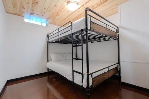 Black metal bunk bed under a pine ceiling and a small window