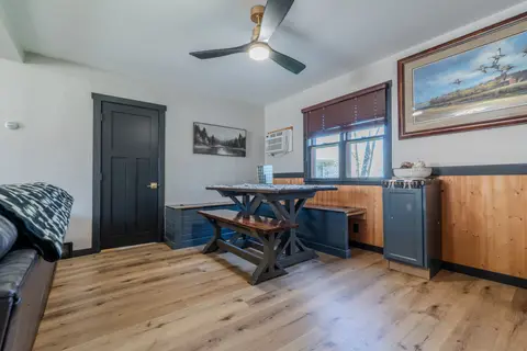 Dining table and bench beside a leather sofa and a wood-paneled wall