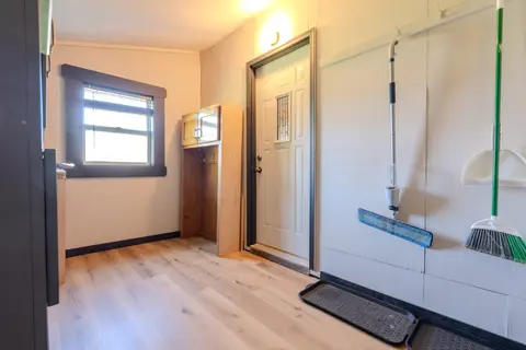 Back entry with a window, a door, and a broom and mop on hooks