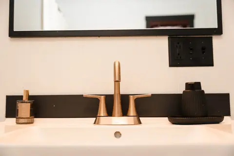 Brass faucet on a white vanity with a black mirror frame