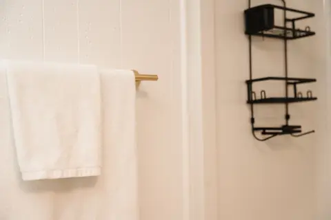 White towel on a brass bar beside a shower caddy