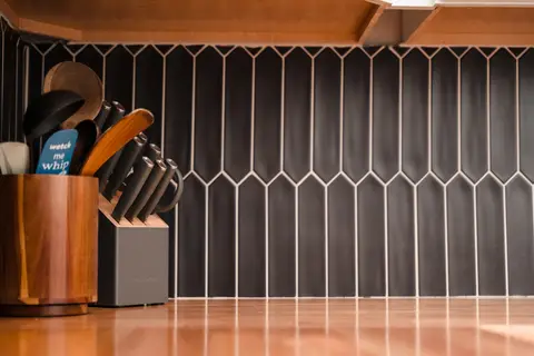 Knife block and utensils against a dark tile backsplash