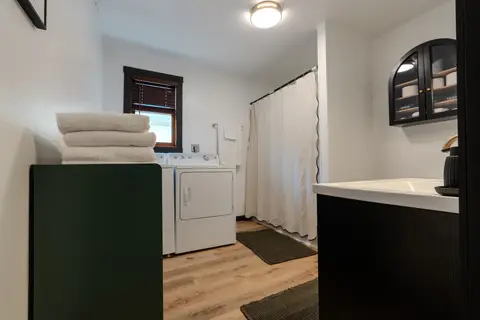 Bathroom with a washer and dryer, stacked towels, and a curtained tub