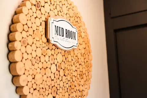 Round log-slice art with a “Mud Room” sign