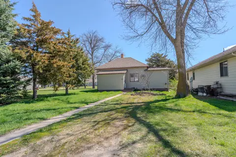 Backyard lawn with tall trees and a path to the rear entry