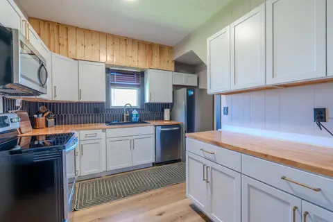 Kitchen with a black range, butcher-block counters, and white cabinets