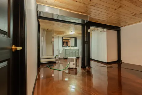 Lower level with a glossy floor, a curtained shower stall, and a vanity at the far end