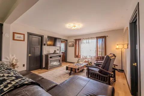 Living room with a leather sofa, two recliners, and a fireplace console under a TV