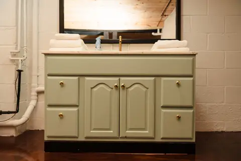 Sage green vanity with a black mirror and fresh towels