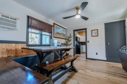 Trestle dining table with benches, a ceiling fan, and a wall air conditioner