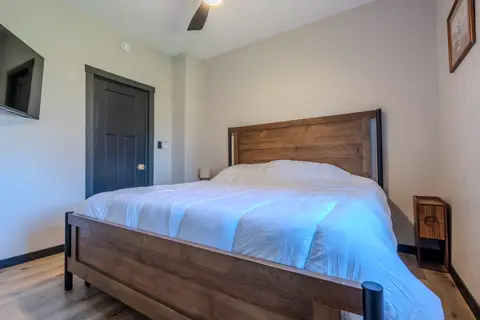 Bedroom with a wood-frame bed, a ceiling fan, and a wall-mounted TV