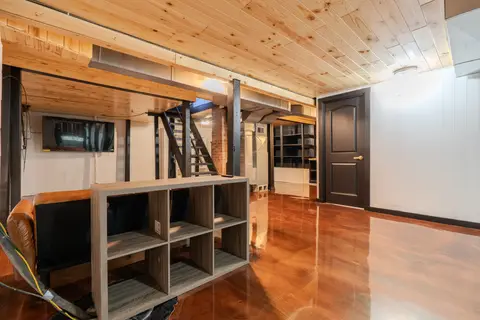 Lower-level sitting area with cube shelves, a TV, and the stairs