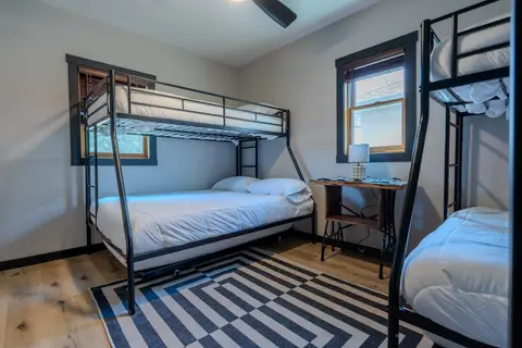 Bunk room with two twin-over-full bunk beds and a striped rug