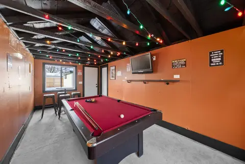 Pool table in the shared game room, with a TV on the orange wall