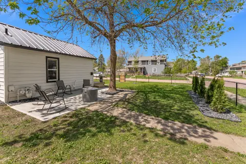 Side patio with rocking chairs and a fire pit beside the house