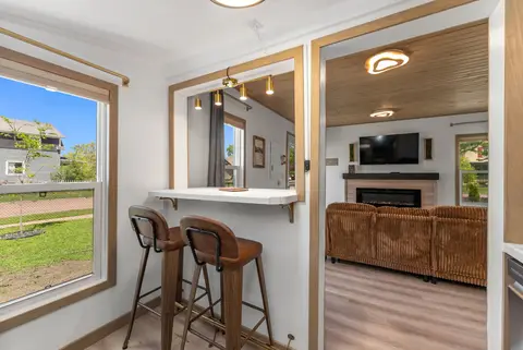 Bar stools at a window counter, looking into the living room with its TV and fireplace