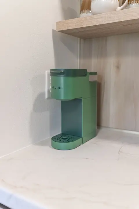 Green single-serve coffee maker on a marble-look counter