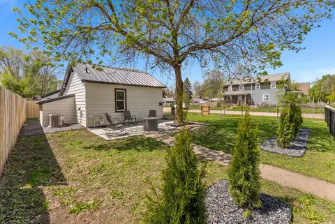 Back of the house from the yard, with the patio and evergreens