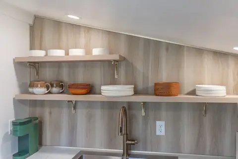 Open shelves with bowls, plates, and mugs above the sink
