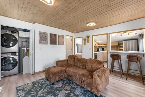Corduroy sectional and bar stools, with a stacked washer and dryer in an open closet