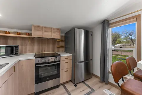 Kitchen with an electric range, stainless fridge, and wood cabinets by a window