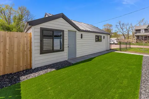Turf side yard along a white building, inside a wood fence