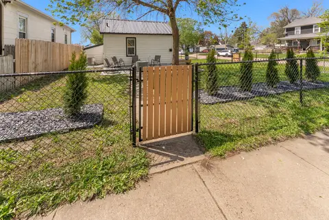 Wood gate in the chain-link fence along the sidewalk