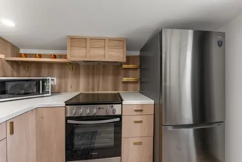 Electric range, microwave, and fridge under wood cabinets