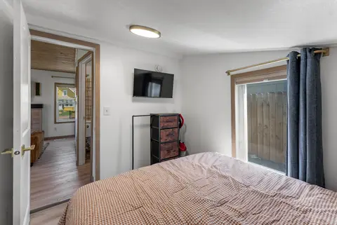 Bedroom with a TV, a chest of drawers, and a curtained glass door