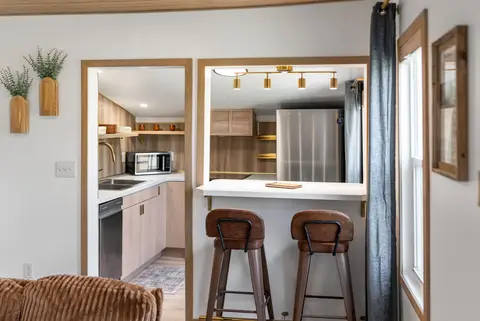 Pass-through counter with bar stools, with the kitchen and fridge behind it