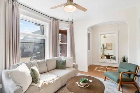 Sunny living room with a sectional, an accent chair, and an arched entry