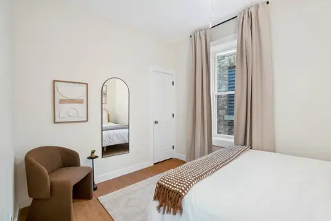 Bedroom with seating, a full-length mirror, and natural textures