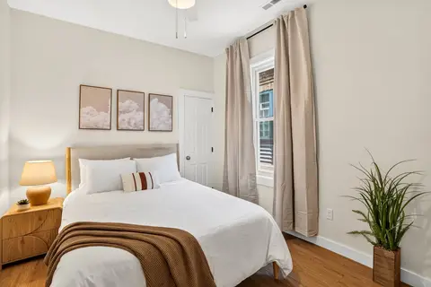 Bright bedroom with neutral tones, cloud artwork, and natural light