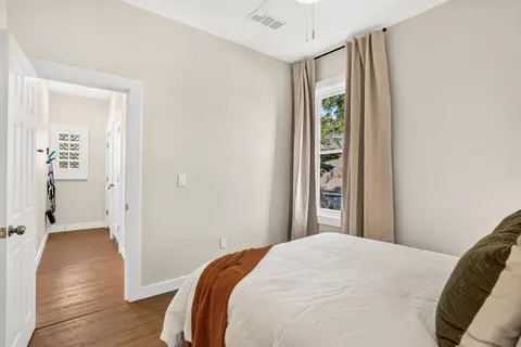 Bright queen bedroom with wood floors
