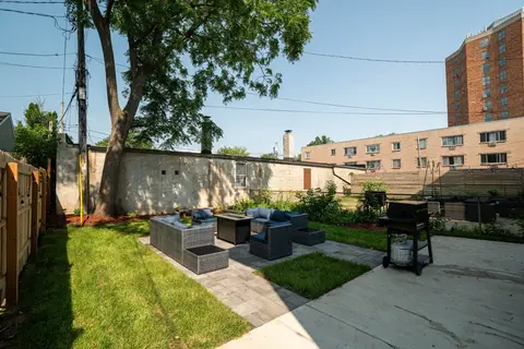 Large backyard with patio seating, a fire table, a grill, and green space