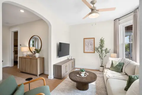 Living room with a large TV, sectional seating, and natural light