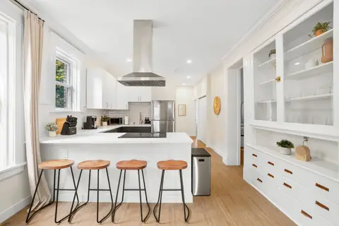 Kitchen with island seating for four, glass-front built-ins, and natural light