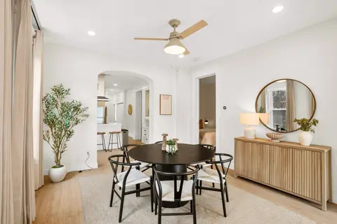 Dining space with a round table, a warm wood sideboard, and access to the kitchen