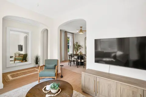 Bright living room with a large TV, accent seating, and arched openings