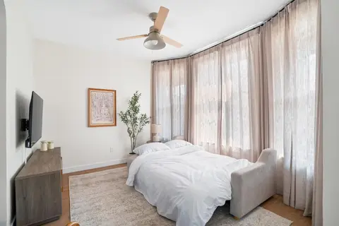 Living room with a sofa bed, a wall-mounted TV, and bay windows