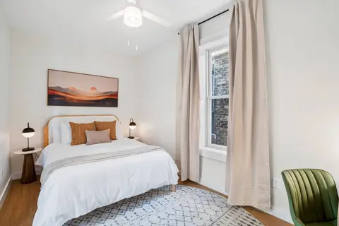 Bright bedroom with sunset artwork and layered bedding