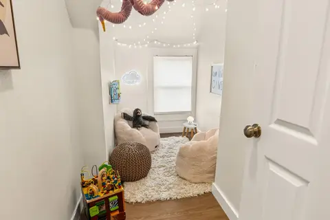 Kids’ reading and play nook with soft seating, books, string lights, and a cloud-shaped light
