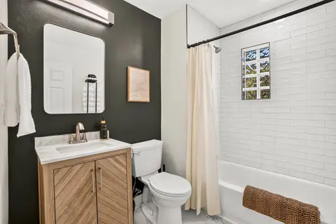 Bathroom with a tub/shower combination, bright tile, and a warm wood vanity