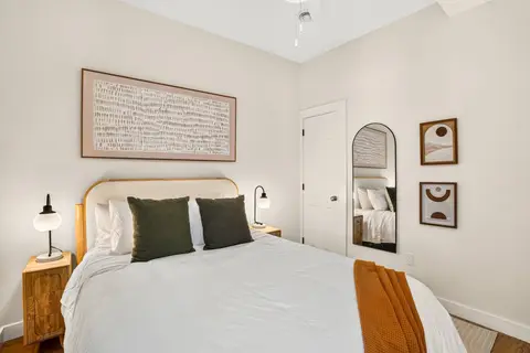 Queen bedroom with green accents, artwork, and a full-length mirror