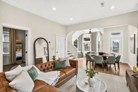 Bright living and dining area with tall windows, warm finishes, and an open layout