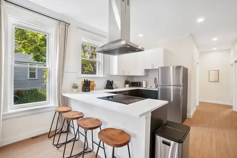 Kitchen with breakfast-bar seating for four and large windows overlooking the trees